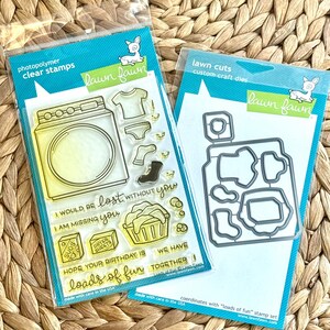 May include: A Lawn Fawn photopolymer clear stamp set and a coordinating metal craft die set. The stamps feature a washing machine, laundry, and text including I WOULD BE LOST WITHOUT YOU, I AM MISSING YOU, and loads of fun in a plastic package.