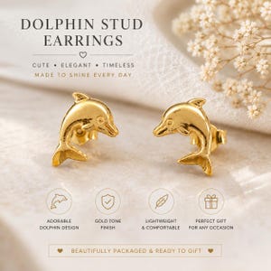 May include: A pair of gold-tone stud earrings shaped like dolphins. The text on the image reads: DOLPHIN STUD EARRINGS, CUTE ELEGANT TIMELESS, MADE TO SHINE EVERY DAY, ADORABLE DOLPHIN DESIGN, GOLD TONE FINISH, LIGHTWEIGHT & COMFORTABLE, PERFECT GIFT FOR ANY OCCASION, BEAUTIFULLY PACKAGED & READY TO GIFT.