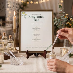 Può includere: Un cartello incorniciato intitolato Welcome to the Fragrance Bar con le istruzioni per un metodo a tre fasi, esposto su un supporto in legno. La scena include piccole bottiglie di vetro etichettate Base Notes, Heart Notes e Top Notes.