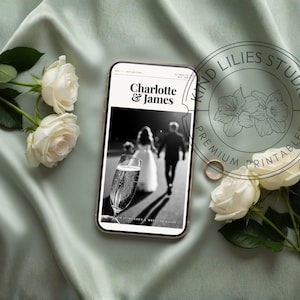 Op de afbeelding: Een smartphone toont een zwart-witte trouwkaart voor Charlotte & James, met een koppel en een champagneglas. De telefoon is omringd door witte rozen en een gouden ring, met een watermerk van Kind Lilies Studio op de afbeelding.