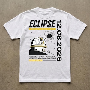 Pode incluir: Uma t-shirt branca de manga curta com um gráfico preto e amarelo de um observatório sob um eclipse solar. O texto diz ECLIPSE, 12.08.2026, TOTALITY 02 MIN 18 SEC, ICELAND, SPAIN, PORTUGAL, FIRST OVER EUROPE SINCE 1999, PATH OF TOTALITY.