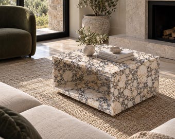 Può includere: Un tavolino quadrato caratterizzato da un motivo a mosaico con inserti in pietra circolari nei toni del crema, beige e grigio scuro. Il tavolo presenta un design basso con un ripiano rettangolare aperto sotto la superficie.