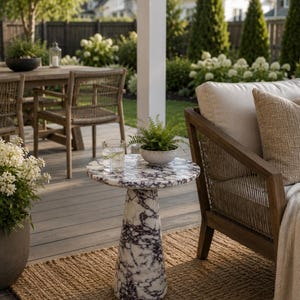 May include: A round side table featuring a white and dark purple marble pattern with a conical base. The table surface holds a small potted green fern and a clear glass of water. The piece is constructed from stone with a polished finish.