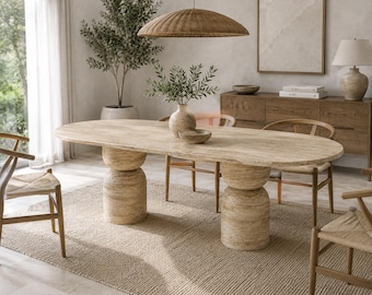 Può includere: Un tavolo da pranzo ovale in pietra di travertino beige con una superficie liscia e due spesse basi cilindriche. Il tavolo è circondato da quattro sedie in legno con sedute intrecciate, caratterizzate da una palette di colori naturali.