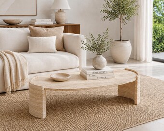 Può includere: Un tavolino da caffè ovale realizzato in pietra travertino beige con una superficie liscia e due gambe curve a semicerchio. Il tavolo presenta una texture naturale porosa e venature marrone chiaro in tutta la sua solida struttura architettonica.