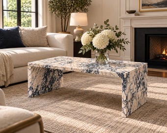 Può includere: Un tavolino rettangolare con design a cascata, realizzato in pietra lucida con un caratteristico motivo marmorizzato di venature color crema, bianco e blu navy intenso su tutta la superficie e sui pannelli laterali.