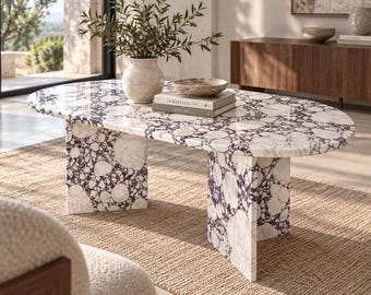 Può includere: Un tavolino ovale caratterizzato da un motivo in marmo brecciato bianco e viola scuro con finitura lucida. Il tavolo è sostenuto da due ampie gambe a lastra in marmo abbinate e presenta una texture in pietra naturale su tutta la superficie.