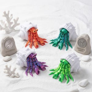 May include: Four articulated hermit crab figures with white shells in orange, teal, purple, and lime green. Two gray stone-like markers are present, one labeled DETACHABLE with a claw icon and one labeled POSEABLE JOINTS with a joint icon.