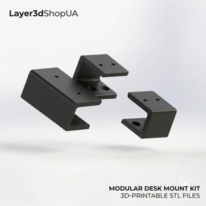 Op de afbeelding: Een set van drie zwarte C-vormige modulaire bureauhouders met voorgeboorde schroefgaten. De tekst Layer3dShopUA staat in de linkerbovenhoek en de tekst MODULAR DESK MOUNT KIT 3D-PRINTABLE STL FILES staat in de rechterbenedenhoek.