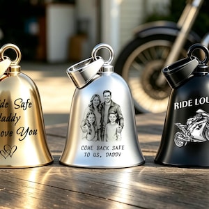 Peut inclure: Trois cloches en métal avec des anneaux au sommet. La cloche dorée porte l'inscription "Ride Safe daddy I Love You" avec deux cœurs. La cloche argentée affiche un portrait de famille et "COME BACK SAFE TO US, DADDY". La noire montre une moto et "RIDE LOUD".