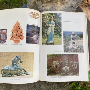 Puede incluir: Un libro abierto en una p&aacute;gina que muestra varios elementos de decoraci&oacute;n de jard&iacute;n, incluyendo una placa de pared de terracota, un banco de jard&iacute;n de hierro forjado, una figura de Martha Washington de hierro fundido, una figura de Pan de plomo, un unicornio de hierro moldeado y una pared de ladrillo con plantas en macetas y una placa de pared de cer&aacute;mica.