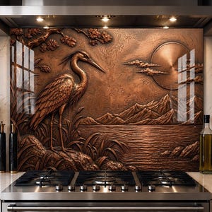 May include: A copper-toned metal backsplash panel featuring a high-relief embossed scene of a heron standing near water, with mountains and a large circular sun in the background. The textured metallic surface displays intricate details of foliage.