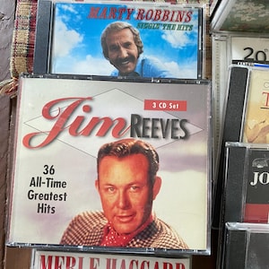 May include: CDs featuring country music artists Marty Robbins, Jim Reeves, and Merle Haggard. The Jim Reeves CD is a 3-CD set with 36 All-Time Greatest Hits. The Marty Robbins CD is titled "Singin' The Hits". The CDs are in clear plastic cases.