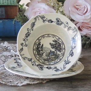 May include: A white ceramic bowl with a black and white floral design. The bowl is sitting on a white lace tablecloth. The bowl is part of a set of dishes.