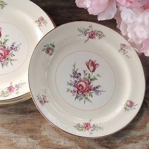 May include: Set of three white ceramic plates with a gold rim and floral design featuring pink and red roses, tulips, and green leaves.