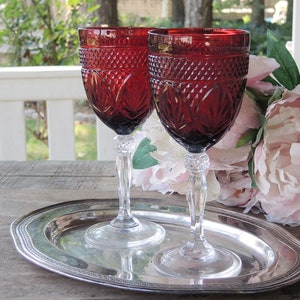 May include: Two ruby red stemmed wine glasses with a diamond pattern on a silver tray.