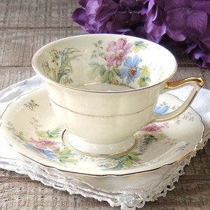 May include: A vintage teacup and saucer set with a floral pattern in shades of pink, blue, and green. The cup and saucer have a gold trim.