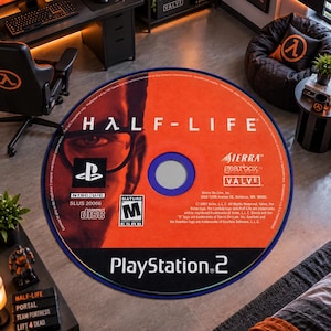 May include: A circular rug featuring the design of a Half-Life video game disc for the PlayStation 2. The orange and black graphic includes the game title, the PlayStation 2 logo, the ESRB Mature rating, and the Sierra, Gearbox, and Valve logos.