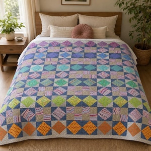 May include: A patchwork quilt featuring a repeating diamond and square pattern in a vibrant spectrum of colours including orange, yellow, green, blue, purple, and pink, set against a neutral beige background with a visible quilted texture.