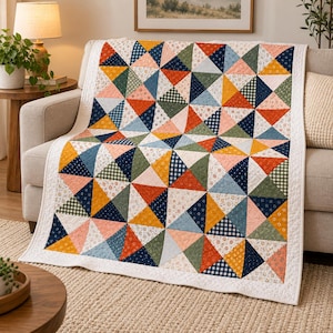May include: A quilt featuring a repeating pattern of triangles in various colours including mustard yellow, navy blue, sage green, and coral pink. The fabric squares display diverse prints such as small floral motifs, gingham checks, and thin stripes.