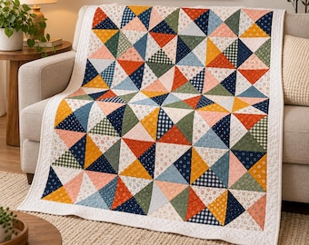 Könnte beinhalten: Eine Steppdecke mit einem sich wiederholenden Muster aus Dreiecken in verschiedenen Farben, darunter senfgelb, marineblau, salbeigrün und korallenrosa. Die Stoffquadrate zeigen diverse Drucke wie kleine Blumenmotive, Vichy-Karos und feine Streifen.