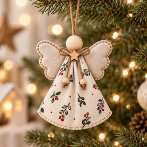 May include: A hanging angel ornament featuring a round wooden head, fabric wings with stitched edges, and a conical dress made of off-white fabric printed with green holly leaves and red berries. A small wooden star sits at the neck with twine.