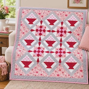 May include: A quilt featuring a repeating pattern of red and pink basket blocks set within gray diamond frames. The background fabric is a light pink print decorated with small red teapots and floral motifs, finished with a gray border.