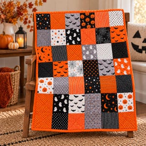 Può includere: Una trapunta patchwork rettangolare caratterizzata da una griglia di quadrati con motivi a tema Halloween, tra cui zucche arancioni, fantasmi bianchi, pipistrelli neri, ragnatele, stelle e lune in una palette di arancione, nero, bianco e grigio.