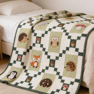 Pode incluir: Uma colcha de retalhos com um padrão repetitivo de quadrados verde-claros e brancos. A colcha é decorada com aplicações bordadas de animais da floresta, incluindo uma raposa, uma coruja, um ouriço e um pinguim, além de cogumelos e bolotas.