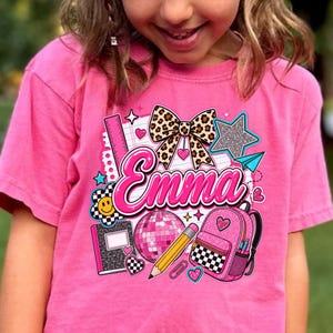 Camiseta infantil personalizada com nome e inicial em estampa de leopardo, camiseta infantil Comfort Colors para a volta às aulas, camiseta mochila com laço Coquette, presente para estudante