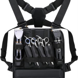 Peut inclure: Un harnais de poitrine noir doté de multiples compartiments pour outils de coiffure professionnels. Le sac contient deux tondeuses électriques, quatre paires de ciseaux de coupe en métal argenté et deux peignes noirs, rangés dans des poches.