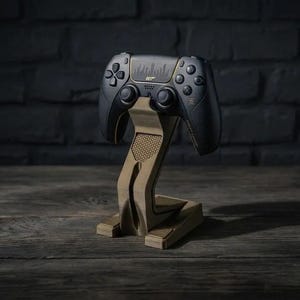May include: A black gaming controller featuring a 007 logo and sound wave graphic, resting on a tan, angular, 3D-printed stand with a hexagonal textured pattern on the neck and base. The controller includes standard buttons, joysticks, and a touchpad.
