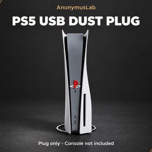 以下が含まれることがあります： PlayStationのロゴが入った赤色の小さな長方形のUSBダストプラグ。白と黒のゲーム機の前面ポートに差し込む設計です。AnonymusLab、PS5 USB DUST PLUG、Plug only, Console not includedというテキストが表示されています。