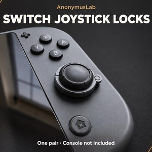 May include: A dark gray gaming controller attachment labeled AnonymusLab SWITCH JOYSTICK LOCKS. The device features a circular black joystick lock mechanism, A, B, X, Y buttons, and a home button. One pair is included, console not included.