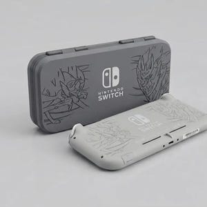 May include: A gray Nintendo Switch handheld gaming console and a matching gray protective carrying case. Both items feature etched line art illustrations of legendary creatures and the Nintendo Switch logo printed in white on the center.