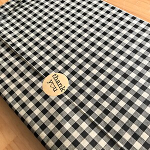May include: A black and white checkered gift wrap with a gold sticker that says "thank you" with a small heart.