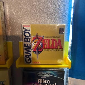 May include: A sealed Nintendo Game Boy video game box for The Legend of Zelda: Link's Awakening. The box features a gold background with the game title in red and black text, a sword and shield graphic, and the official Nintendo Game Boy logo.