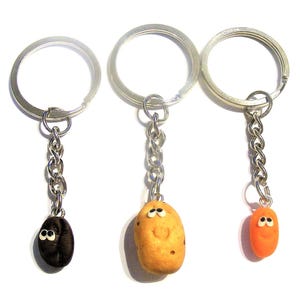May include: Three silver keychains with different potato charms. The charms are brown, orange, and tan with painted eyes and smiles.