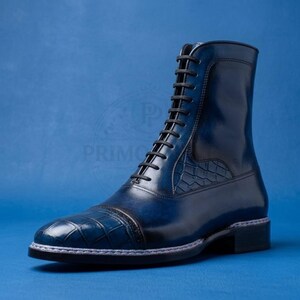Könnte beinhalten: Ein hochgeschlossener Stiefel in tiefblauer Farbverlaufsoptik mit Schnürung und schwarzen Schnürsenkeln. Die Zehenkappe und das Seitenteil weisen ein strukturiertes Prägemuster auf. Der Stiefel hat einen Absatz und eine sichtbare Rahmennaht.