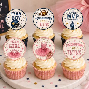 Puede incluir: Seis cupcakes con adornos circulares de papel para una fiesta de revelación de género. Los adornos presentan temas de fútbol y ballet con textos como Team Boy, Team Girl, Touchdowns or Tutus y Little MVP on the Way, en azul y rosa.