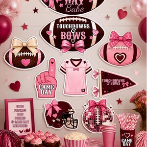 Puede incluir: Una colección de decoraciones de fiesta con temática de fútbol en rosa y marrón, incluyendo recortes de balones con lazos, una camiseta, un dedo de espuma, un casco y una bola de discoteca. El texto incluye GAME DAY Babe, TOUCHDOWNS & BOWS.