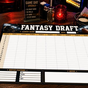 May include: A black and white fantasy football draft board featuring a large grid with twenty rounds, ten team columns, and sections for league name, date, roster positions, and notes. The board has a football helmet and football graphic.