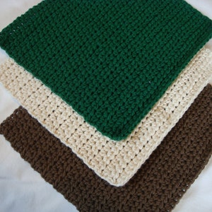 May include: Three crocheted dishcloths in green, cream, and brown. The cloths are stacked on top of each other.