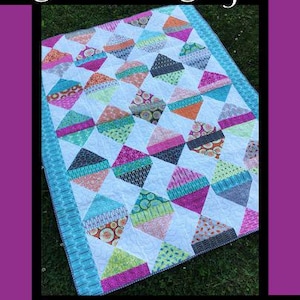 May include: A quilt pattern titled Diamond Daze by Tricia Lynn Maloney for Orphan Quilt Designs and Villa Rosa Designs. The quilt features a repeating diamond motif in various colorful patterned fabrics set against a white background.