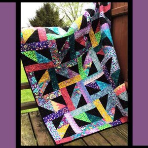 May include: A quilt pattern cover titled Sisterhood by Tricia Lynn Maloney for Orphan Quilt Designs and Villa Rosa Designs. The image features a colorful patchwork quilt with black geometric accents and vibrant multi-colored fabric strips.