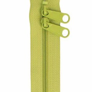 May include: A lime green zipper with two pull tabs. The zipper is closed and ready to be sewn into a garment or project.
