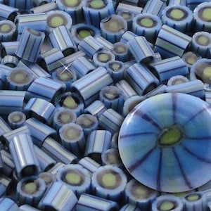 May include: A close-up of blue and white striped candy with a green center. The candy is arranged in a pile, with a single blue and white candy with a green center in the center of the image.