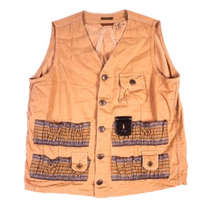 May include: A tan utility vest featuring a V-neckline, a front button closure, and multiple pockets. The garment includes two large lower pockets with gathered, multi-colored striped fabric panels and smaller buttoned flaps for added storage.