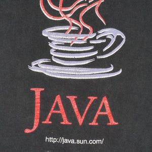 May include: A black t-shirt featuring a graphic of a light purple coffee cup with red steam. Below the cup, the word JAVA is printed in large red letters, followed by the text http://java.sun.com/ and the white Sun logo with a geometric icon.