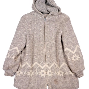 May include: A light brown and cream zip-up hooded jacket featuring a knit texture and a repeating geometric pattern along the hem and sleeves. The garment includes long sleeves with ribbed cuffs, a front zipper closure, and a hood.